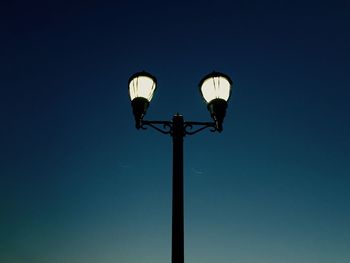 Low angle view of illuminated street light against blue sky