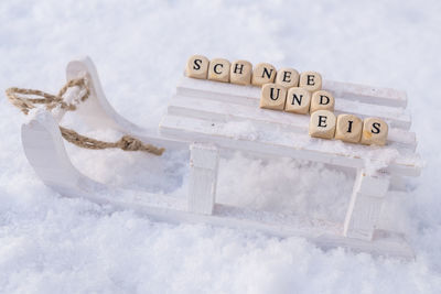 Close-up of text with toy blocks on sled over snow covered field