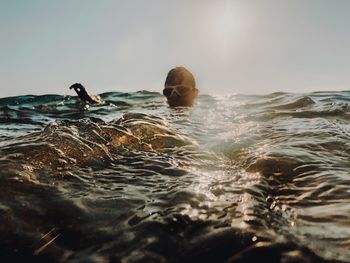 Man swimming in sea against sky