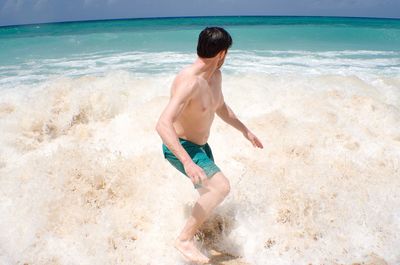 Rear view of shirtless man standing on beach