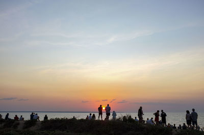 People on beach against sky during sunset