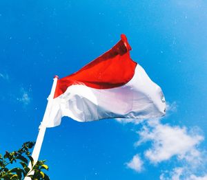 Low angle view of flag against blue sky