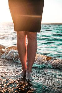 Low section of woman standing in sea