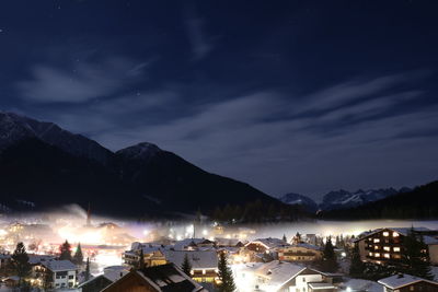 Town by mountain against sky at night