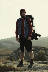 Portrait of young man standing on mountain against sky