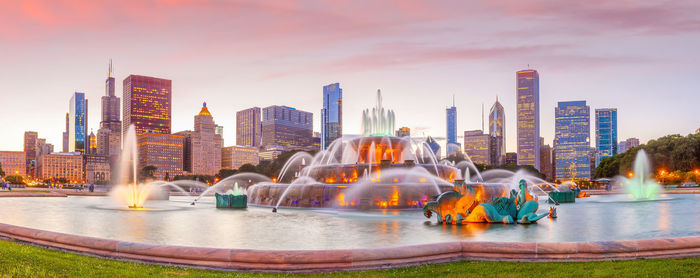 Panoramic view of fountain and buildings against sky during sunset