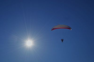 Low angle view of person paragliding against clear blue sky