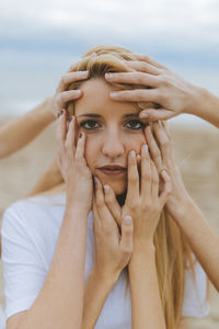 Close-up portrait of woman with hands against sky