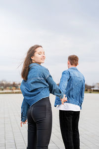 Young loving couple wearing jeans spending time together in the park having fun, woman holding hands