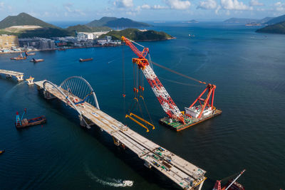 Aerial view of crane constructing bridge in bay