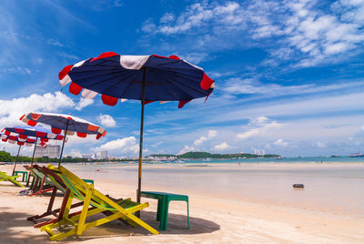 Deck chairs on beach against sky