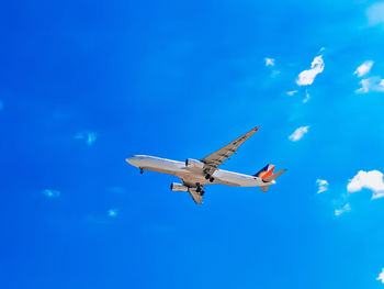 Philippine airlines aircraft on final approach at naia. low angle view of airplane against blue sky.