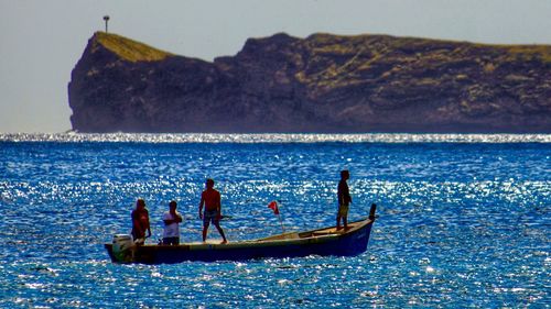 People on boat sailing in sea against sky