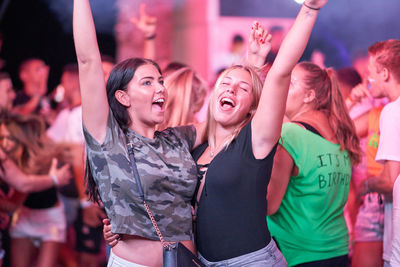 Cheerful female friends enjoying during music festival at night