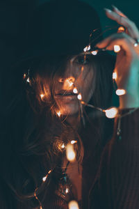 Close-up portrait of woman with illuminated hair at night