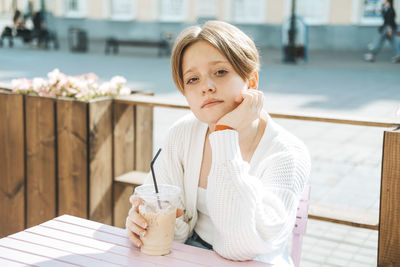 Portrait of young woman sitting on table