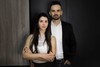 Portrait of young couple standing against wall