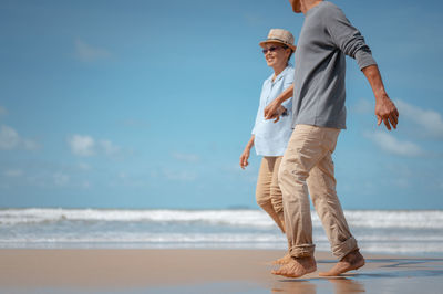 Rear view of man on beach against sky