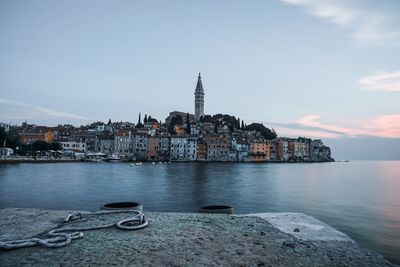 View of buildings by sea against sky in city