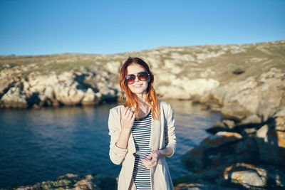 Portrait of smiling young woman standing on rock