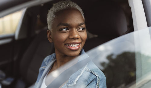 Smiling woman sitting in car looking out through window