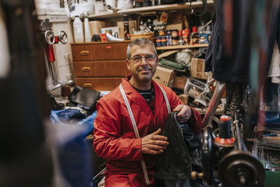 Portrait of smiling locksmith with leather working in repair shop