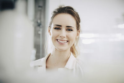 Portrait of smiling young female student standing in laboratory