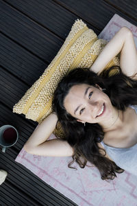 Portrait of smiling woman lying down with hands behind head in balcony