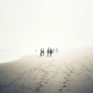 People walking on beach against sky