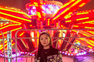 Portrait of young woman in amusement park ride at night