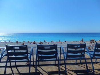 People on beach against clear blue sky