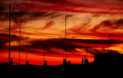 Low angle view of silhouette communications tower against dramatic sky during sunset