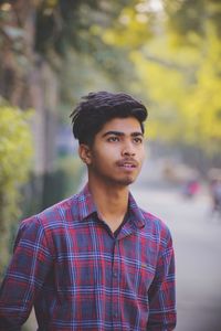 Young man looking away standing on street