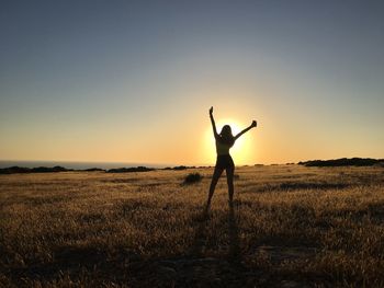 Full length of silhouette teenage girl standing on field against sky during sunrise