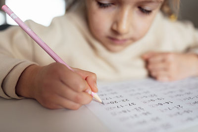 Midsection of girl writing in book