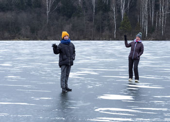 Full length of mature woman standing with daughter on frozen lake