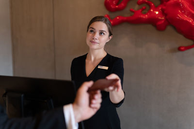 Female receptionist receiving room key from businessman before departing from hotel