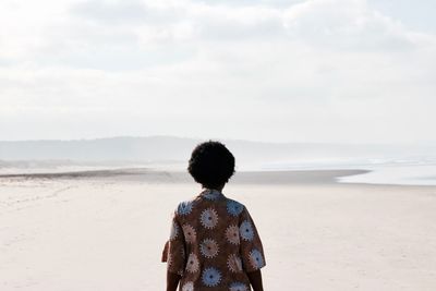 Rear view of woman at beach against sky