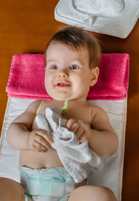 Cute baby girl holding napkin while lying down at home