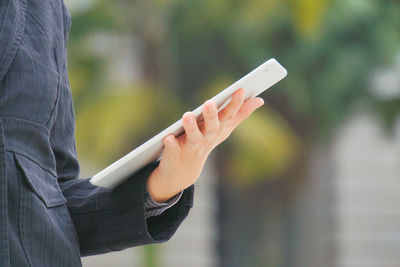 Midsection of person holding digital tablet outdoors