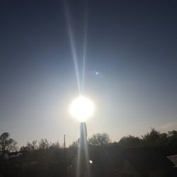 Sunlight streaming through trees against sky on sunny day