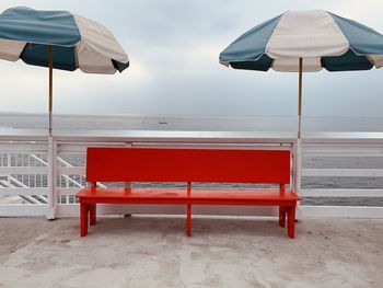 Empty chairs on beach against sky