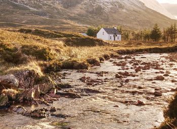 Cottage nestled below buachaille etive mor alongside river coupall near glencoe, higlands, scotland.