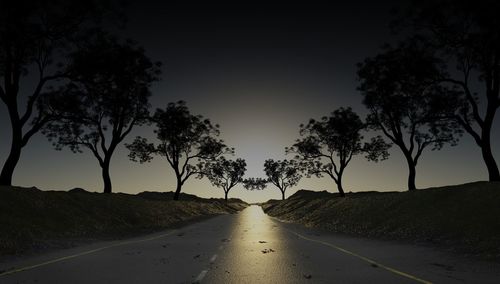 Empty road amidst silhouette trees at dusk