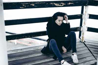 Woman sitting on pier at beach