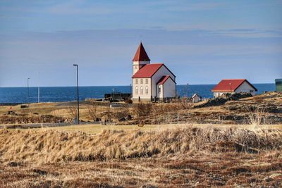 House on field by sea against sky