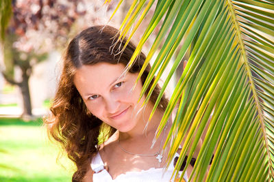 Portrait of young woman with palm leaves