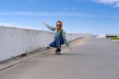 Full length of young woman standing on road against sky