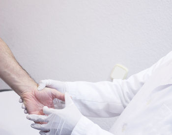 Midsection of doctor holding patient wrist at hospital