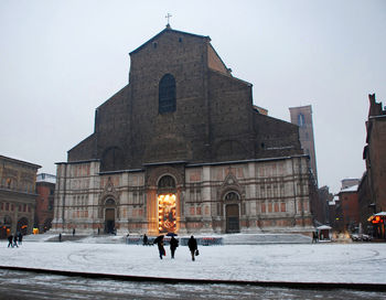 People in front of building against sky during winter